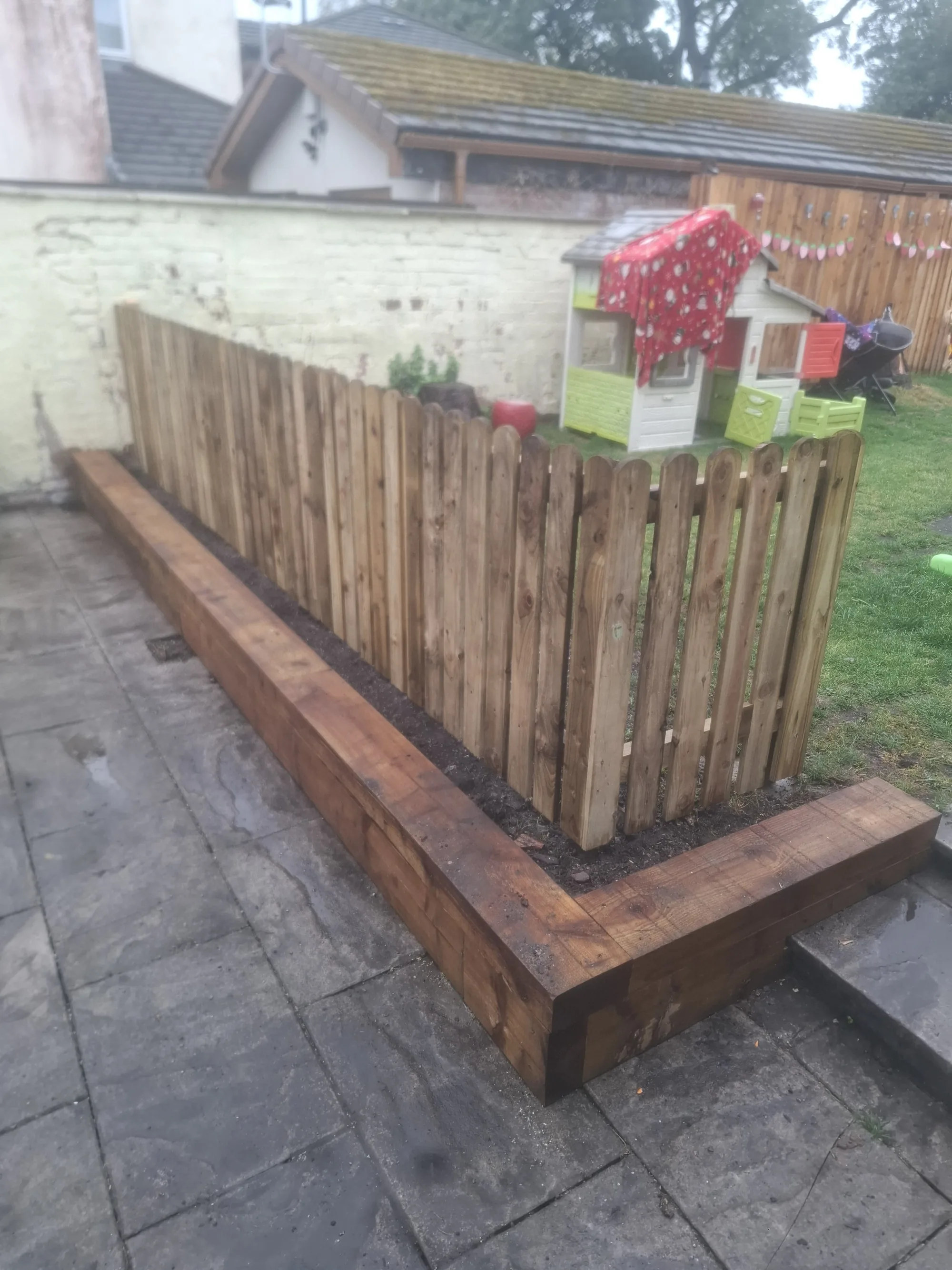 Picket fence with a timber sleeper raised bed
