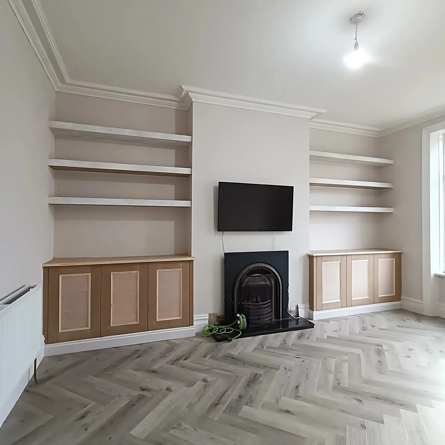 Alcove cupboards and floating shelves either side of a fireplace