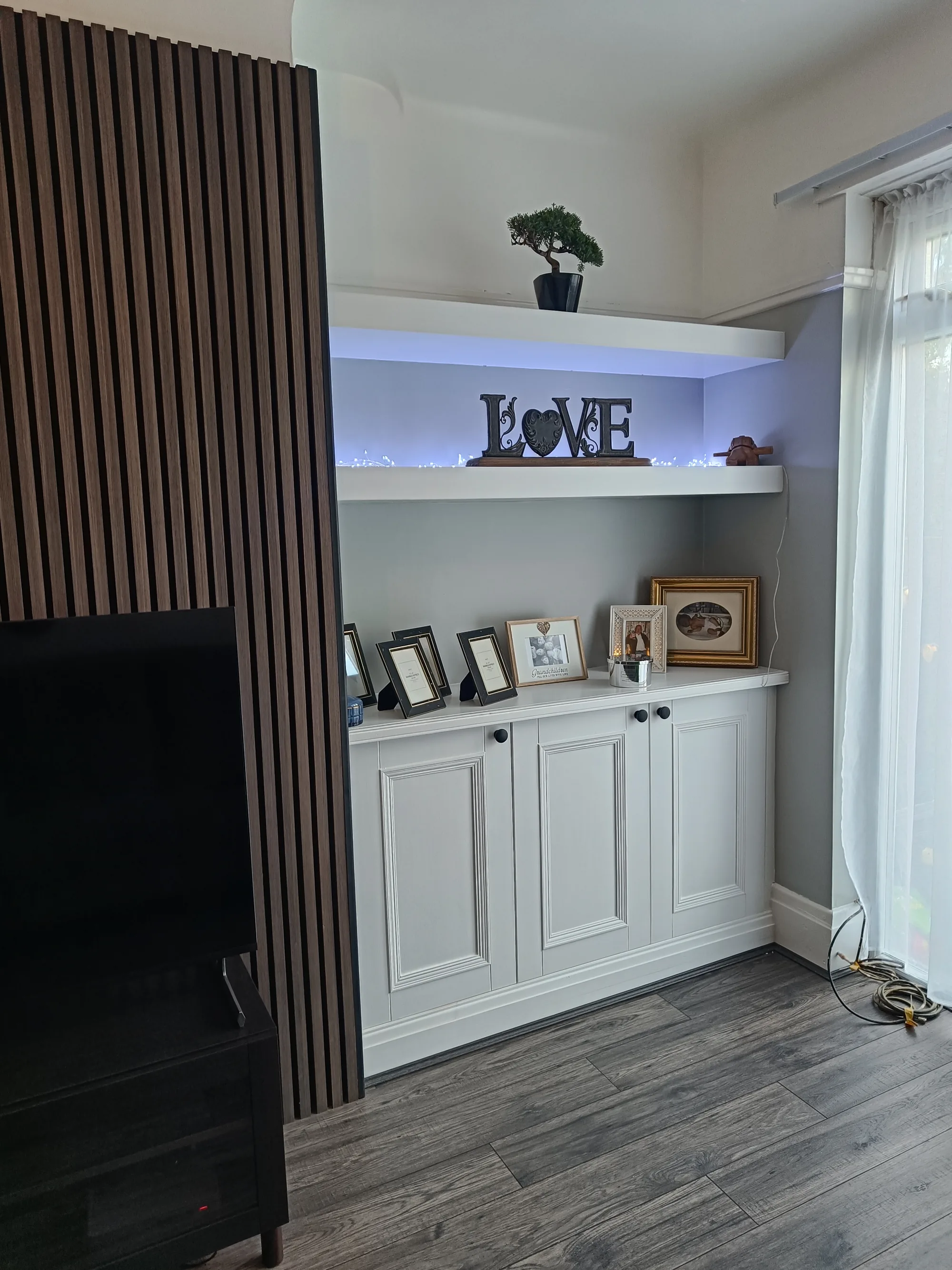 Painted alcove cupboard with lit floating shelves and a slatted wall panel