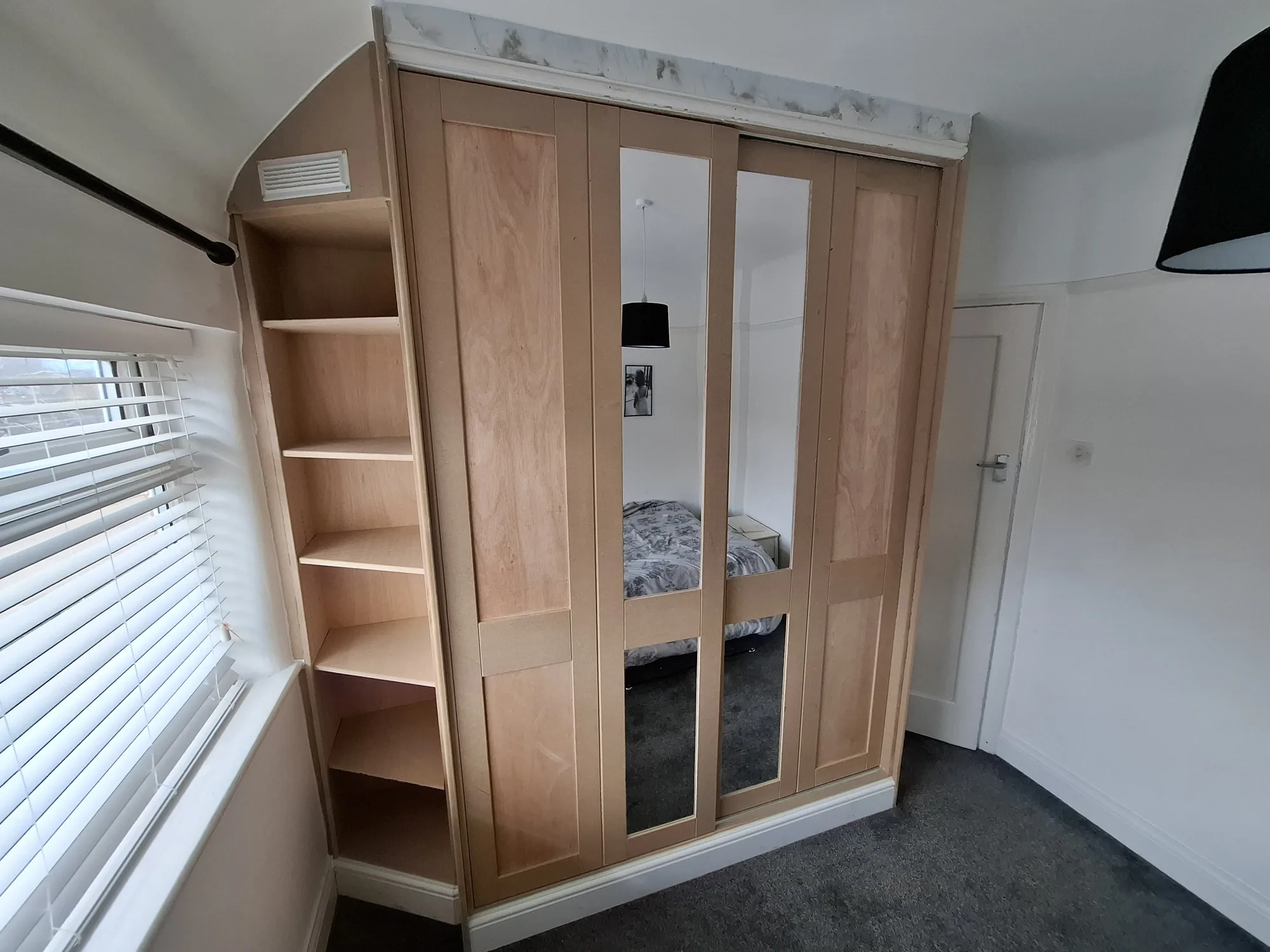 Fitted wardrobe with mirror doors and open end shelving